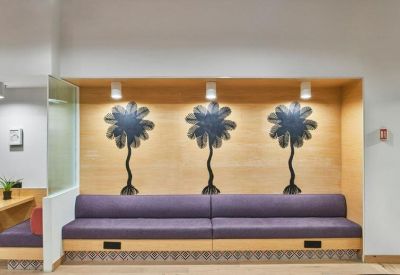 Purple velvet bench seating in a recessed wall nook decorated with three stylized tree motifs.