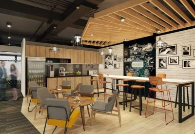 Communal kitchen and breakout area with a long high-top table, bar stools, and chalkboard wall.