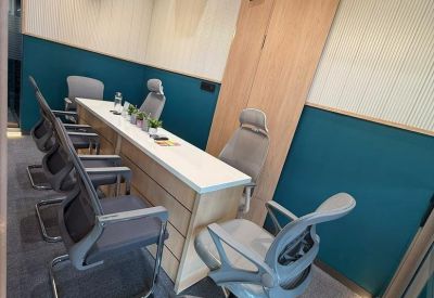Narrow conference or training room with a long desk and several grey ergonomic chairs.