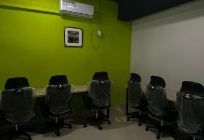 Office workspace with a row of desks against a lime green feature wall with an AC unit.