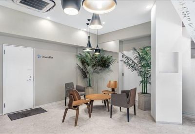 Modern lounge area with wooden chairs, round table, and indoor greenery.