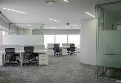 Wide open-plan work area with carpeted floors and modern white workstations.