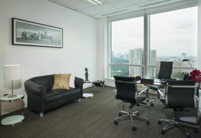 Executive corner office with a black leather sofa, desk, and expansive city views.