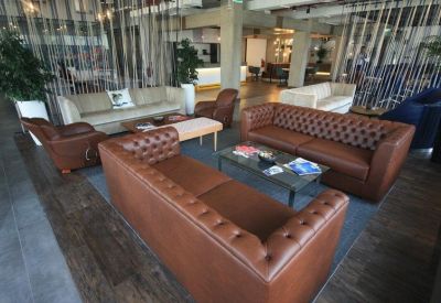 Spacious lounge with brown leather chesterfield sofas and wooden flooring.