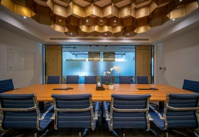 Large boardroom with a wooden table, blue chairs, and a geometric honeycomb ceiling.
