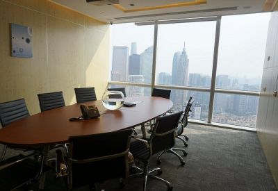 Modern boardroom with an oval wooden table and panoramic city skyline views.