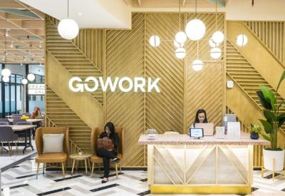 Bright reception area with a wood-paneled feature wall, branded signage, and comfortable leather armchairs.