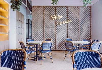 Cafe-style breakout area with blue woven chairs, round tables, and a wooden slat feature wall.