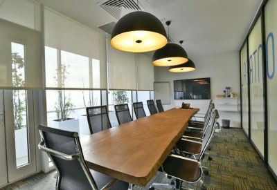 Professional meeting room with a long wooden table and ergonomic black mesh chairs.