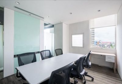Professional meeting room with a white conference table, black chairs, and a glass whiteboard.