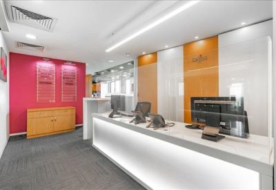 Modern reception desk with a bright pink feature wall and wood cabinetry.