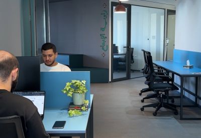 Open-plan workspace featuring blue desk dividers and ergonomic seating.