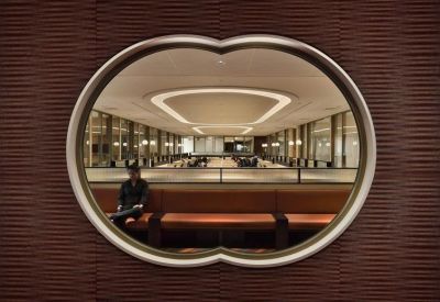 Unique decorative wall opening looking into a large, bright open-plan office space.