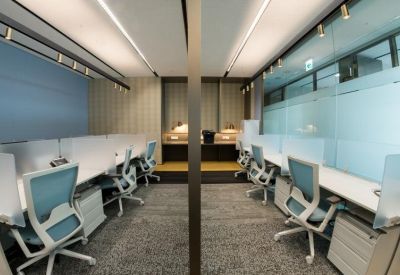 Symmetrical coworking area featuring white desks and blue chairs divided by a central glass partition.