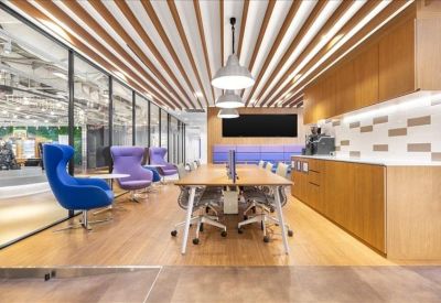 Modern coworking space with a wooden slatted ceiling and colourful armchairs.
