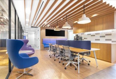 Open-plan office area featuring long wooden desks and blue privacy dividers.
