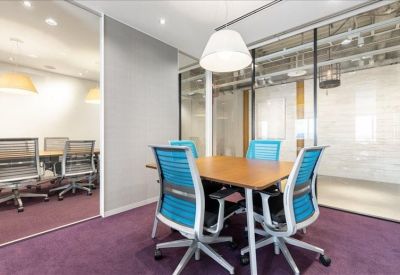 Small meeting room with four blue chairs and a glass wall partition.