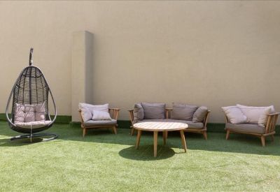 Outdoor terrace lounge with artificial grass, wicker furniture, and a hanging egg chair.