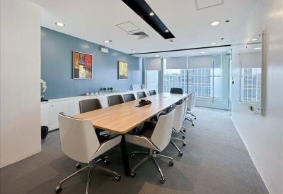 Professional boardroom with a long wooden table and sleek white chairs.