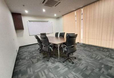 Professional meeting room with a wooden table, black chairs, and a whiteboard.