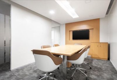 Professional meeting room with a light wood table, stylish chairs, and a wall-mounted TV.