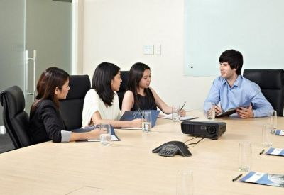 Business meeting in a bright conference room with a large wooden table and professional seating.