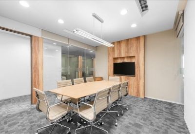Modern conference room with a light wood table, grey carpet, and recessed TV.