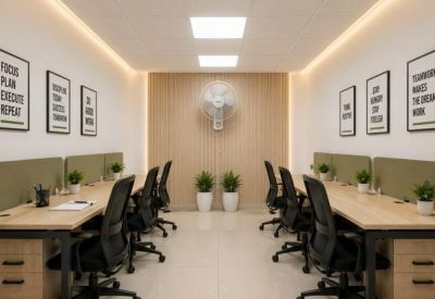 Bright coworking office with wooden desks, black chairs, and motivational posters on the walls.
