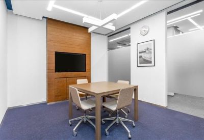 Modern breakout room with a central wooden table and a wall-mounted television.