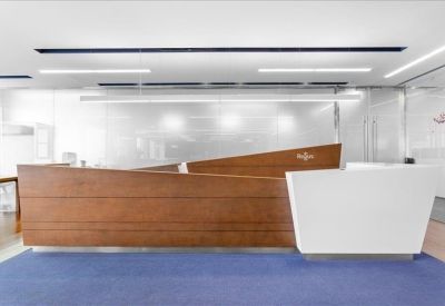 Sleek reception desk combining warm wood panels and a minimalist white counter.