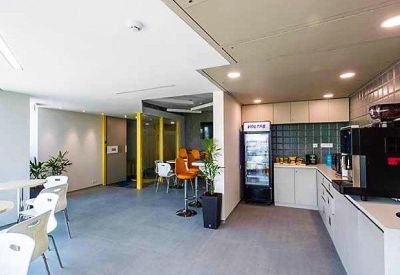 Modern communal kitchen and breakout area with high-top seating and a coffee station.