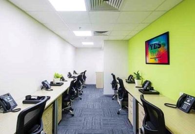 Bright open-plan office space with green accent walls and dedicated workstations.