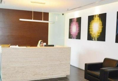 Reception area with a light-colored stone desk and abstract light-themed wall art.
