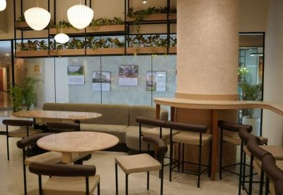 Contemporary breakout area with round wooden tables, high stools, and hanging globe lights.
