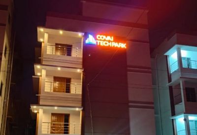 Exterior view of the multi-story Covai Tech Park building at night with glowing orange and blue signage.