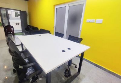Bright meeting room featuring a white conference table, black chairs, and a vibrant yellow feature wall.