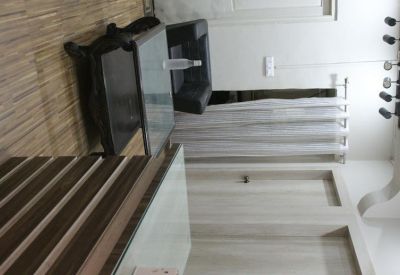 Waiting area with a glass-top table, dark leather sofa, and wood-paneled wall accents.