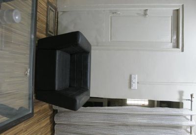 A simple waiting room view with a black leather armchair and a white wall with an electrical outlet.