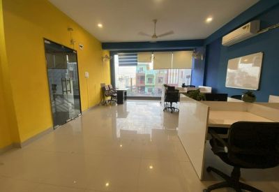Open-plan office area with polished floors and a yellow accent wall near the glass entrance.