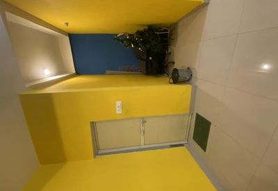 Entrance corridor with bright yellow walls leading to a glass-paneled door.