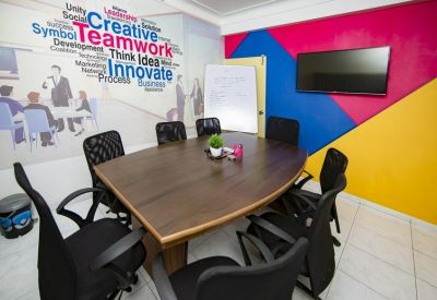 Small meeting room featuring a wooden table and a colourful geometric accent wall.