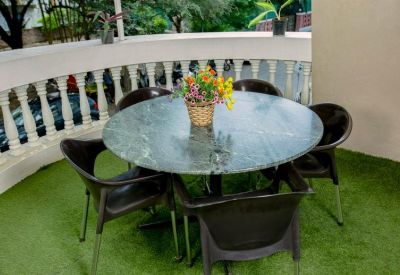 Outdoor round stone table with four chairs on a green turf balcony.