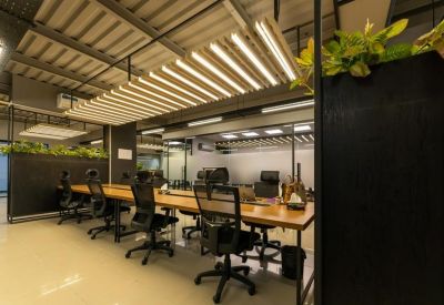 Long communal wooden desk with professional task lighting and a decorative plant feature wall.