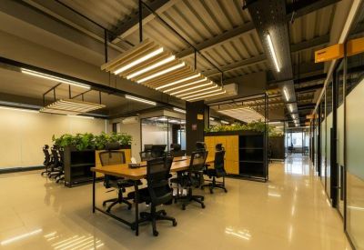 Spacious open-plan workspace featuring wooden desks, ergonomic chairs, and indoor greenery.