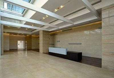 Bright reception lobby with a white and black desk under a modern beam ceiling.