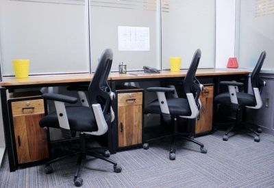 Three-person workstation with black mesh chairs and light wood desks.