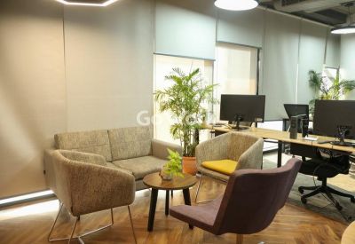 Modern lounge area with grey sofas, armchairs, and a round coffee table near large windows.