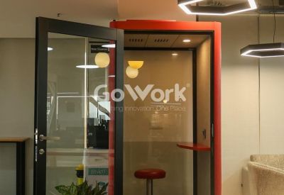 Red private phone booth with a glass door and stool for quiet calls.