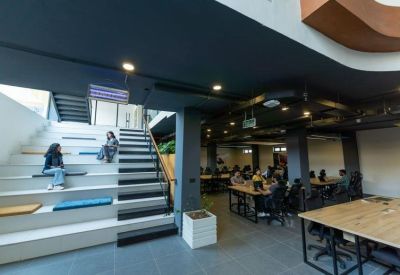 Modern coworking space featuring a tiered seating staircase and open-plan wooden desks.