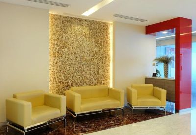 Lounge waiting area with yellow armchairs and a decorative textured feature wall.